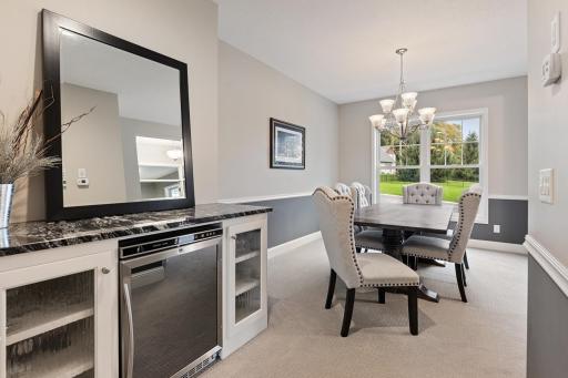 Elegant formal dining room complemented by a butlerâs pantry featuring a wine fridge, abundant storage, and an extended counter area.