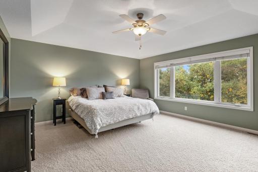 Large upper-level primary bedroom with serene views of the private, tree-lined backyard.