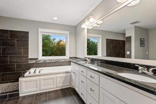 Primary bathroom features a dual-sink vanity, relaxing soaking tub, and spacious walk-in shower.