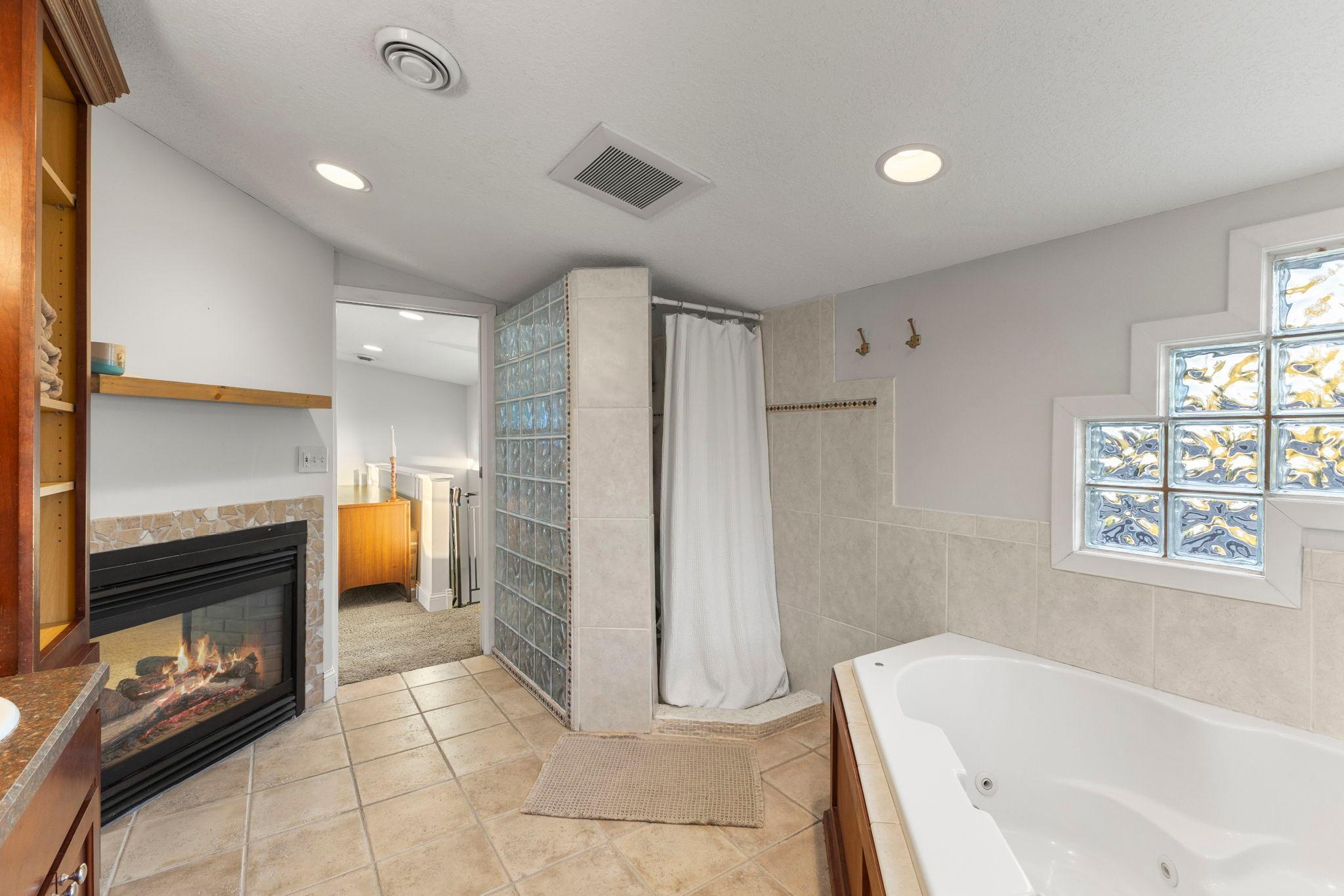 Private bath with ceramic floor, see through fireplace, jetted tub and separate shower