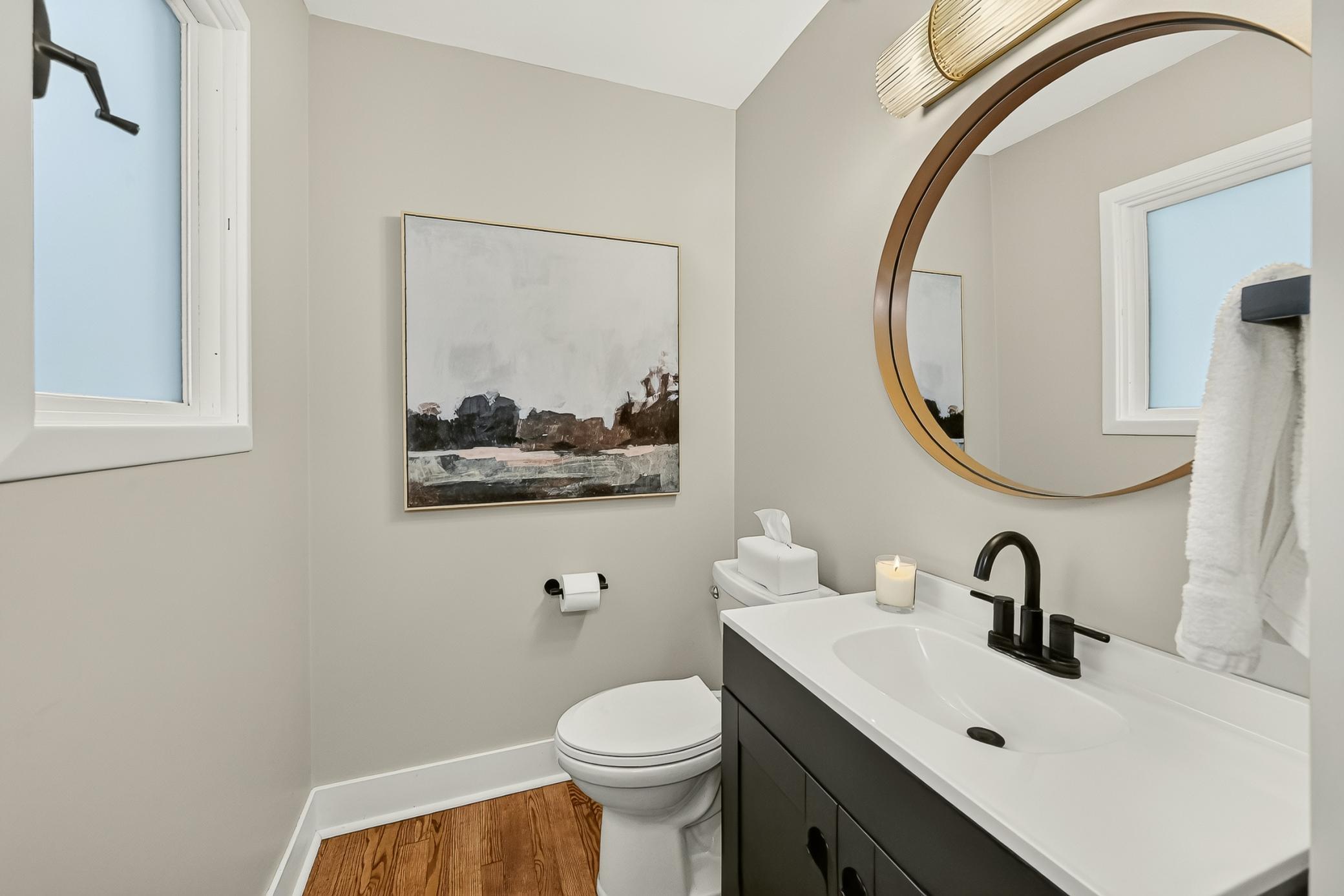 Main floor half bath with new vanity, lighting and hardwood floors.