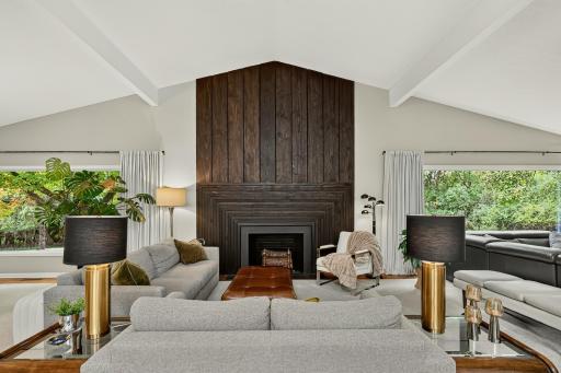 Soaring vaulted ceilings and an impressive wall of glass greet you, bringing the outdoors in, framing the custom wood fireplace surround.