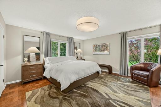 Bright and spacious primary bedroom with peaceful private views, new lighting, and beautiful parquet flooring.