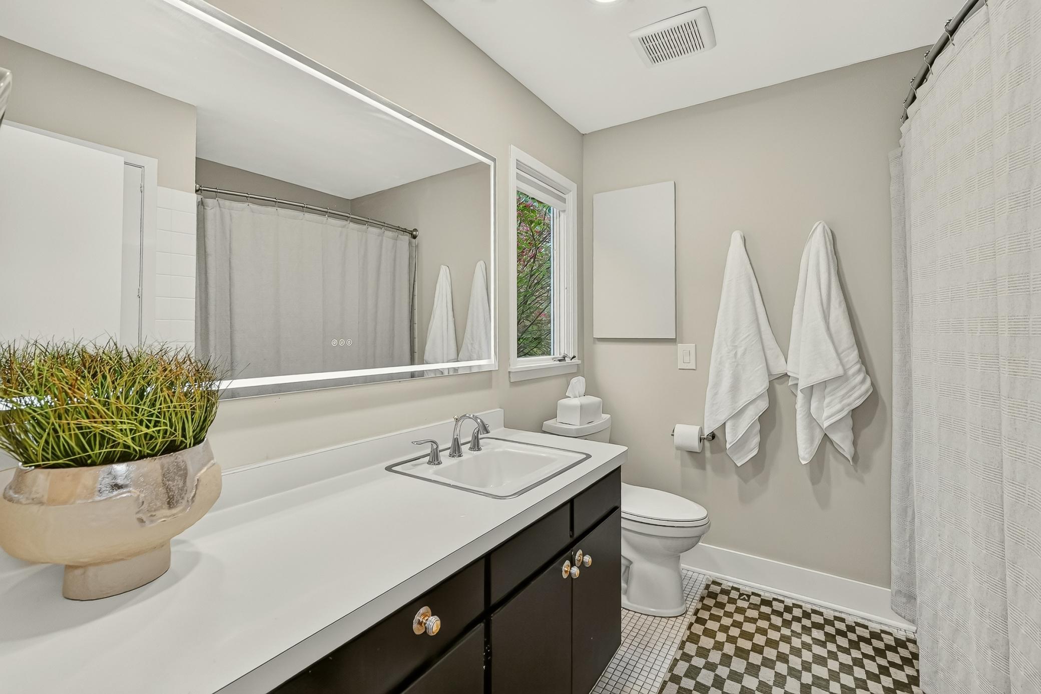 Light-filled full private ensuite with an expansive vanity, statement illuminated mirror and minimalist modern feel.