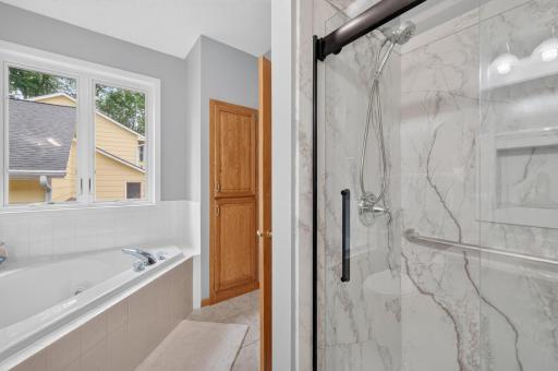 Newer custom walk in shower with grab bars, niche box and full glass shower door in the main floor full bathroom.