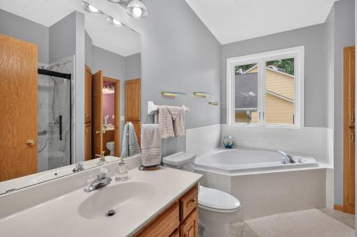 The main floor bathroom offers a corner whirlpool tub with window above it, linen closet ceramic tiled floor and newer shower.