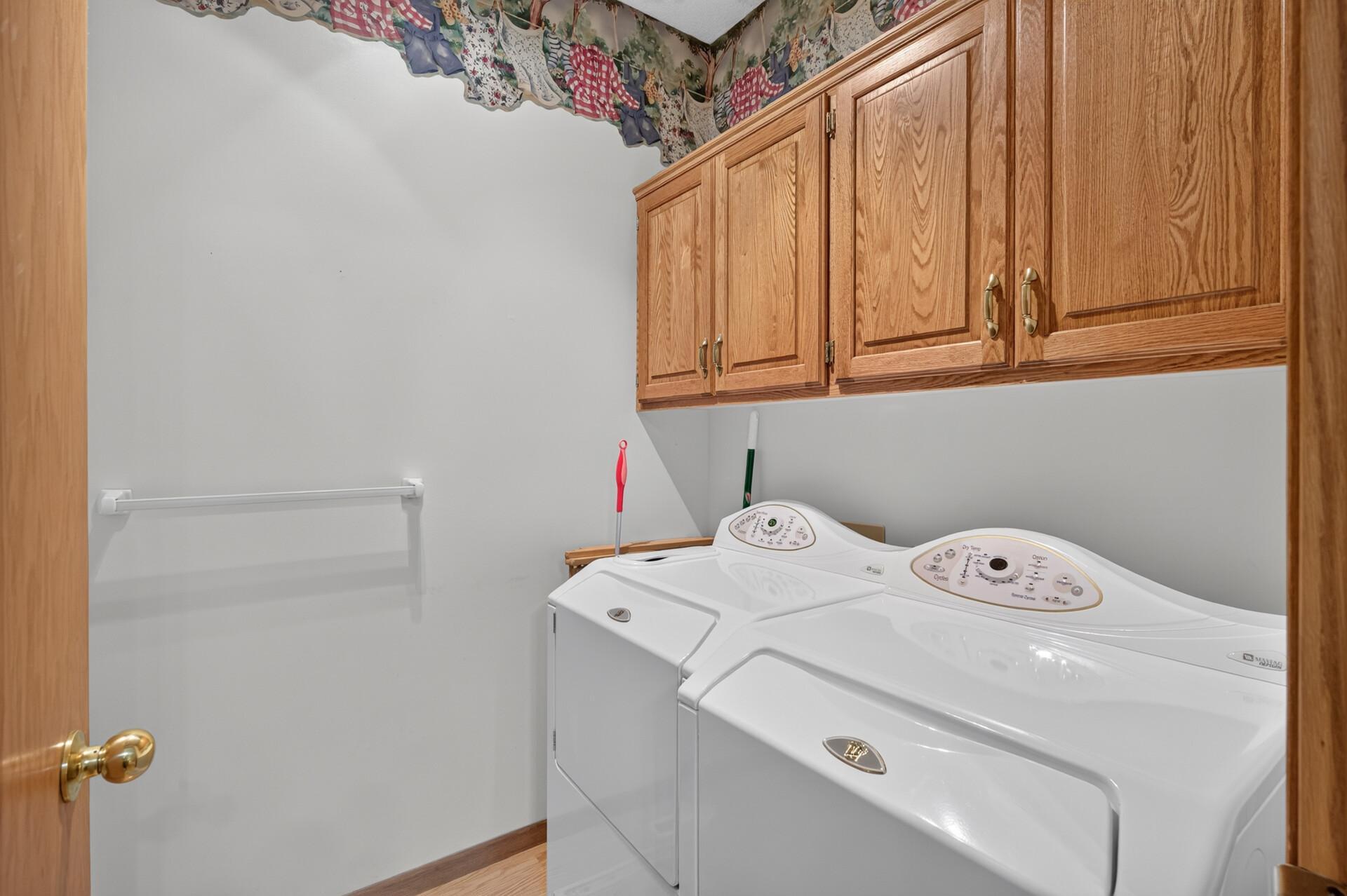 Main floor laundry room with nice upper storage cabinets above the washer and dryer. There is a folding counter behind the door.