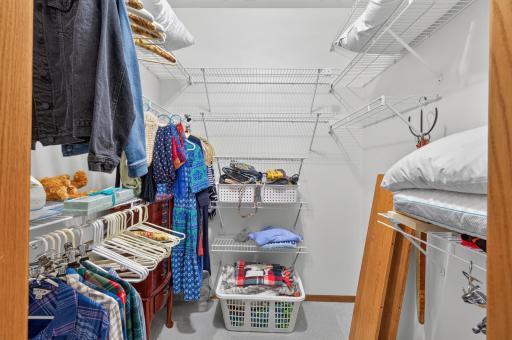 Primary walk in closet with lots of shelving.