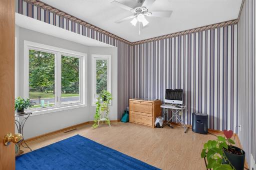 Large bayed window in the front bedroom/office with a ceiling fan.