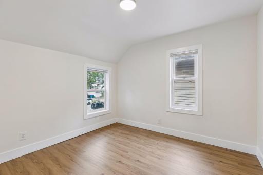 Unit 1: The second upper-level bedroom offers two windows for natural light, updated flooring, and overhead lighting.