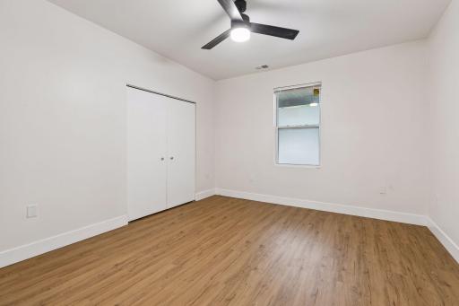 Unit 1: A bright and comfortable main-floor bedroom with updated flooring, a ceiling fan with light, and a double closet for extra storage.