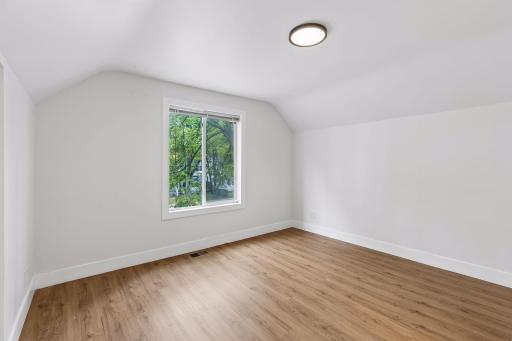Unit 1: Two more bedrooms await upstairs! This first bedroom offers updated flooring, overhead lighting, and plenty of natural light.