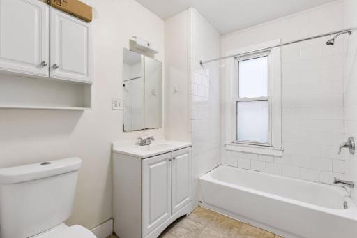 Unit 2: This main floor full bath features a tub/shower combo, window, vanity, and cabinet storage for added functionality.