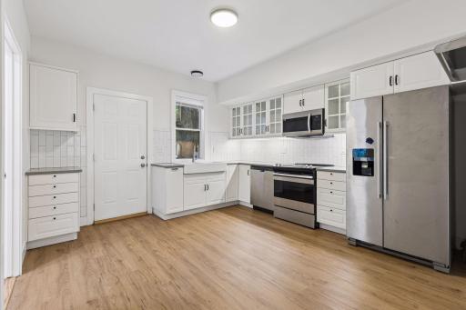 Unit 1: Stylish and functional kitchen features updated flooring, stainless steel appliances, overhead lighting, and abundant cabinet and counter space