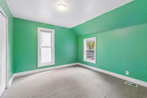 Unit 2: The second upper-level bedroom features carpet flooring, overhead lighting, and windows that bring in natural light.