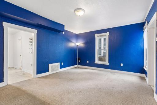 Unit 2: A spacious living room with carpet flooring, overhead lighting, and windows providing plenty of natural light.