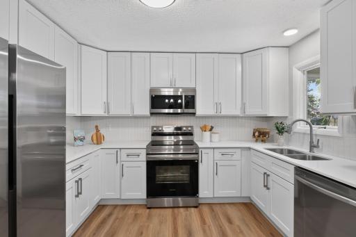 Main level: brand new kitchen cabinets, quartz counters, backsplash, stainless appliances, and LPV