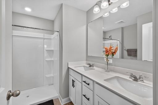 The private primary bathroom features a spacious vanity with ample countertop space, a large mirror, and a convenient shower/tub combination.