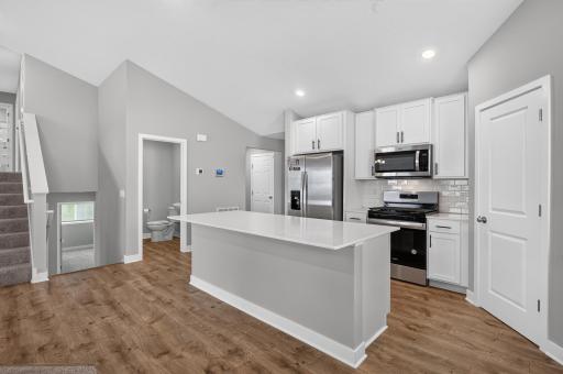 Designed with both style and functionality in mind, the kitchen features a large quartz center island that serves as the heart of the home. Enjoy ample countertop space, additional seating, and easy access to the surrounding living areas