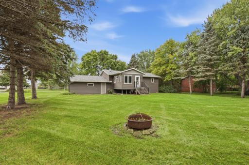 The backyard is a wonderful extension of the home, featuring mature landscaping, plenty of room to enjoy the outdoors, a spacious lawn, and a dedicated bonfire area.