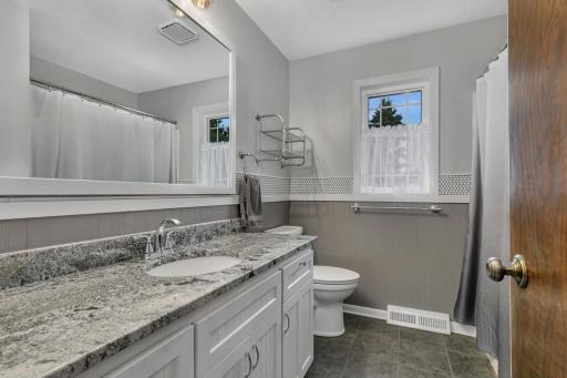 The full upper-level bathroom includes tiled flooring, granite countertops, an updated toilet, and a spacious built-in linen cabinet.