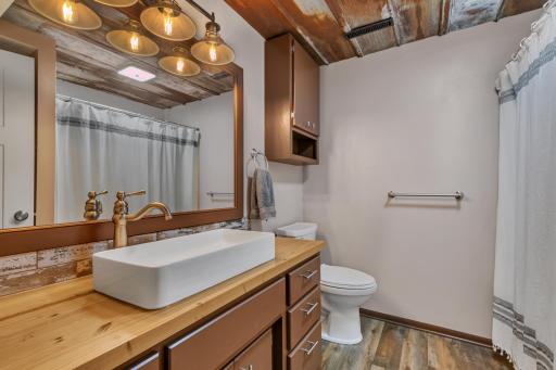 The recently remodeled lower-level bathroom has been updated from floor to ceiling, including the flooring, mirror and lighting, vanity, sink, faucet, exhaust fan, toilet, and tub/shower.