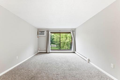 Spacious living room features neutral finishes and large sliding glass doors that bring in natural light and frame the treetop view.