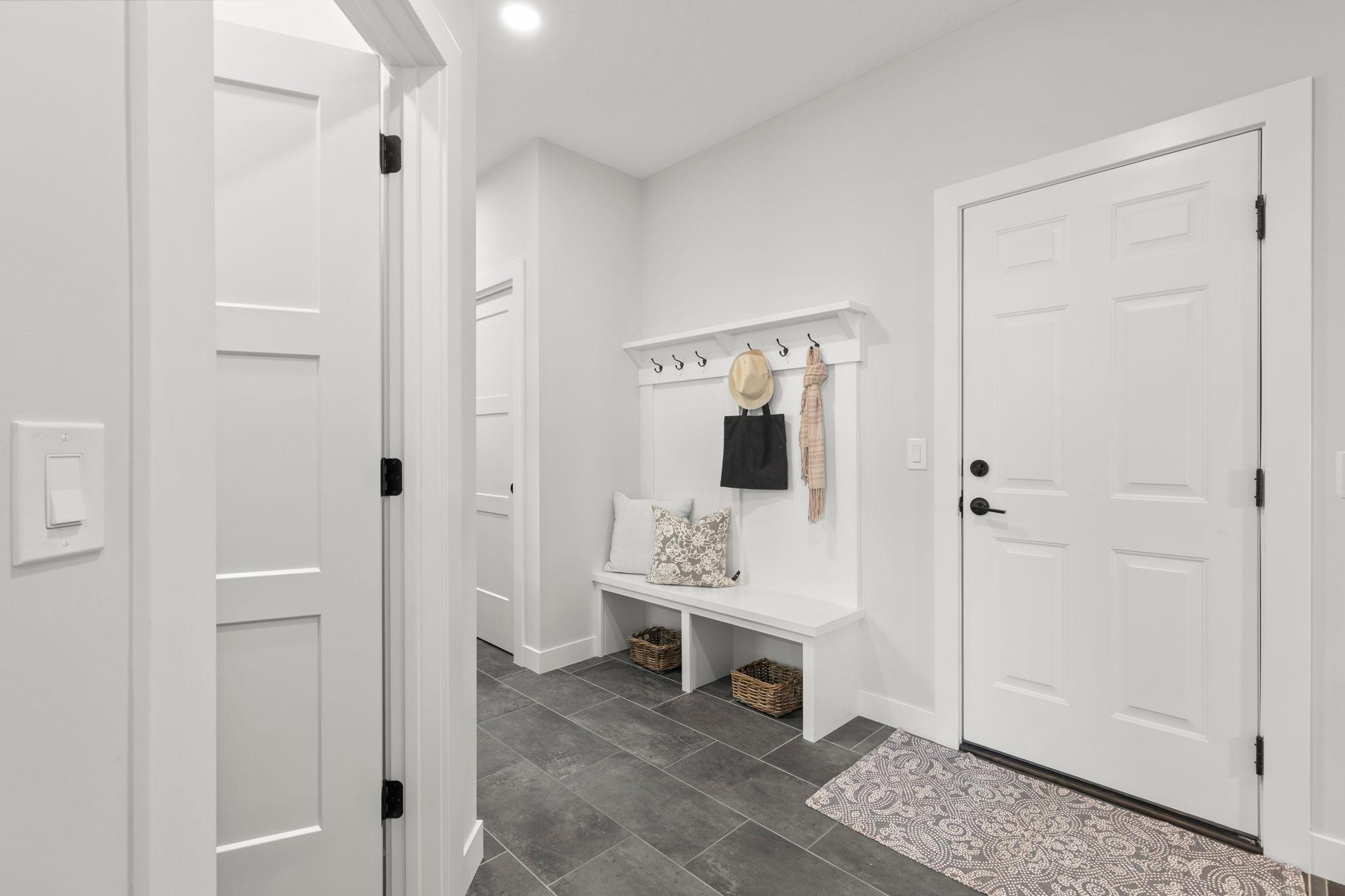 Rounding out the main level is a spacious garage entry and mudroom with ample closet storage, a built-in bench with hooks, and durable tile flooring.