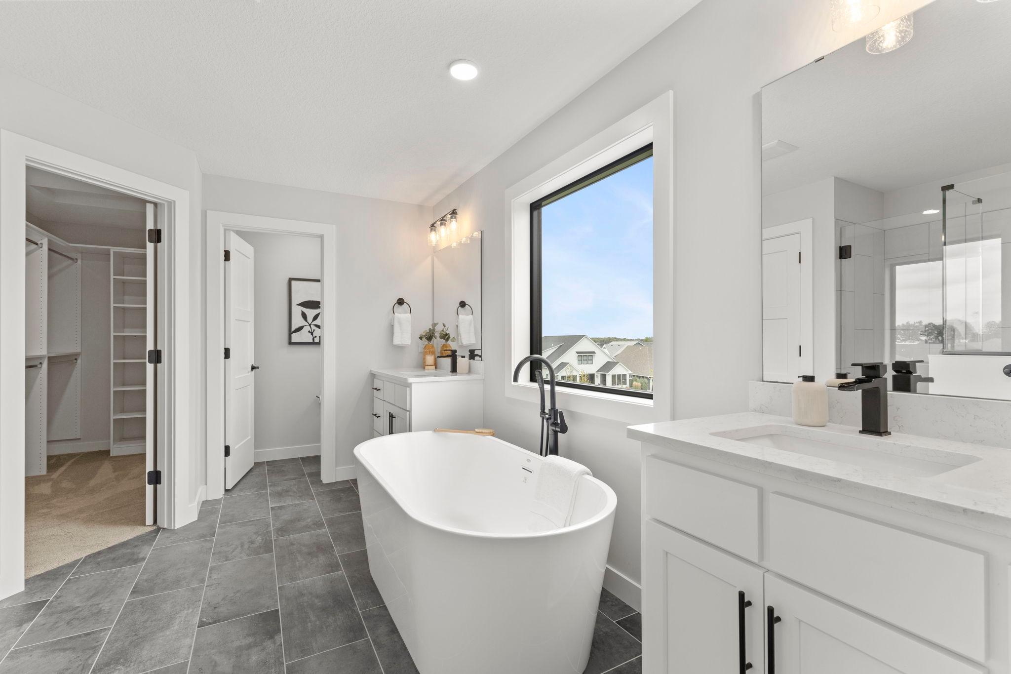 The luxurious ensuite bathroom offers an oversized soaking tub, spacious tiled walk-in shower, heated tile flooring, and an expansive walk-through closet with built-ins providing exceptional wardrobe storage.