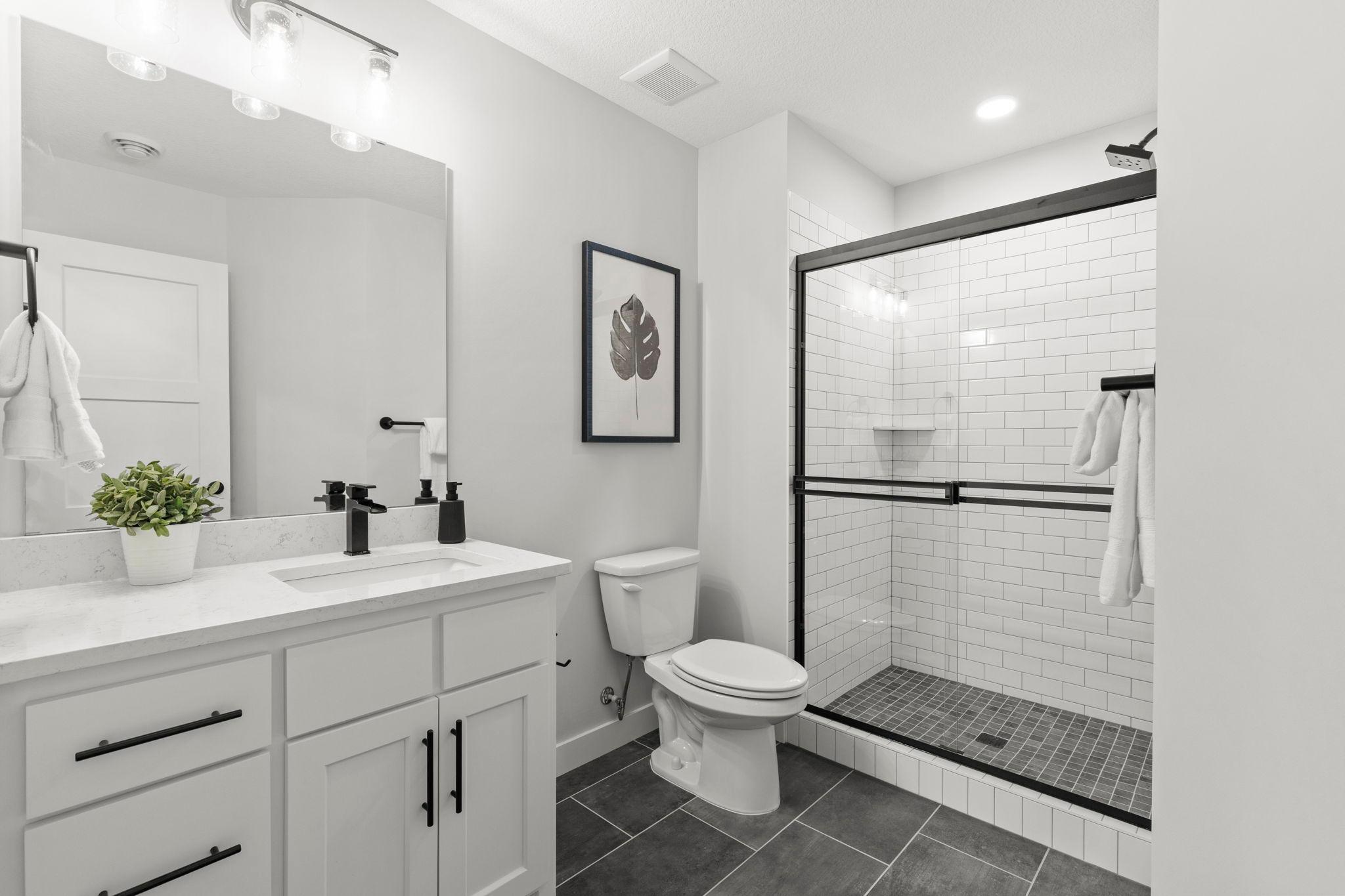 A nearby ¾ bathroom features a tiled walk-in shower and single vanity.