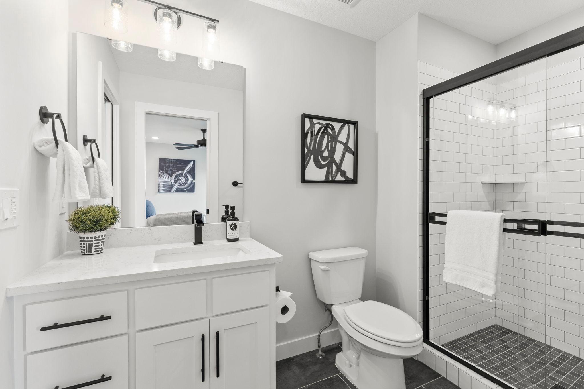 The walkthrough ¾ bathroom offers a tiled walk-in shower and single vanity.