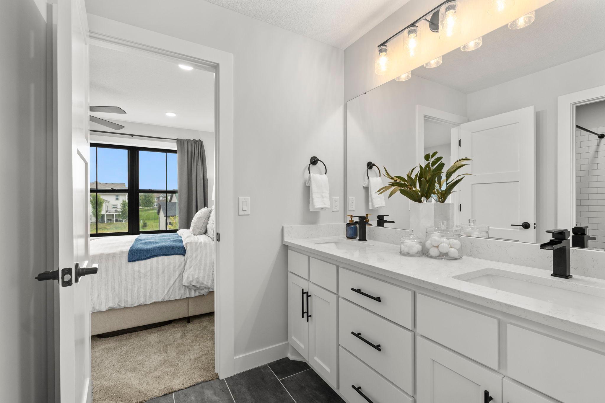 The Jack-and-Jill bathroom features a dual vanity, tile flooring, and a separate water closet with a tub and shower combination.
