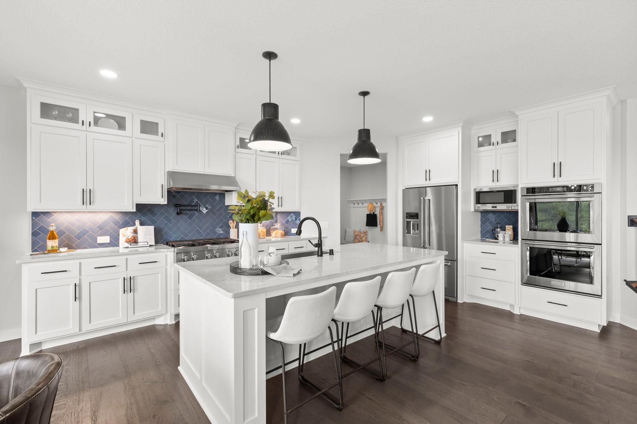 The kitchen is a true chef’s dream, featuring abundant white cabinetry, quartz countertops, and a spacious center island with an apron-front sink, breakfast bar seating, and pendant lighting.