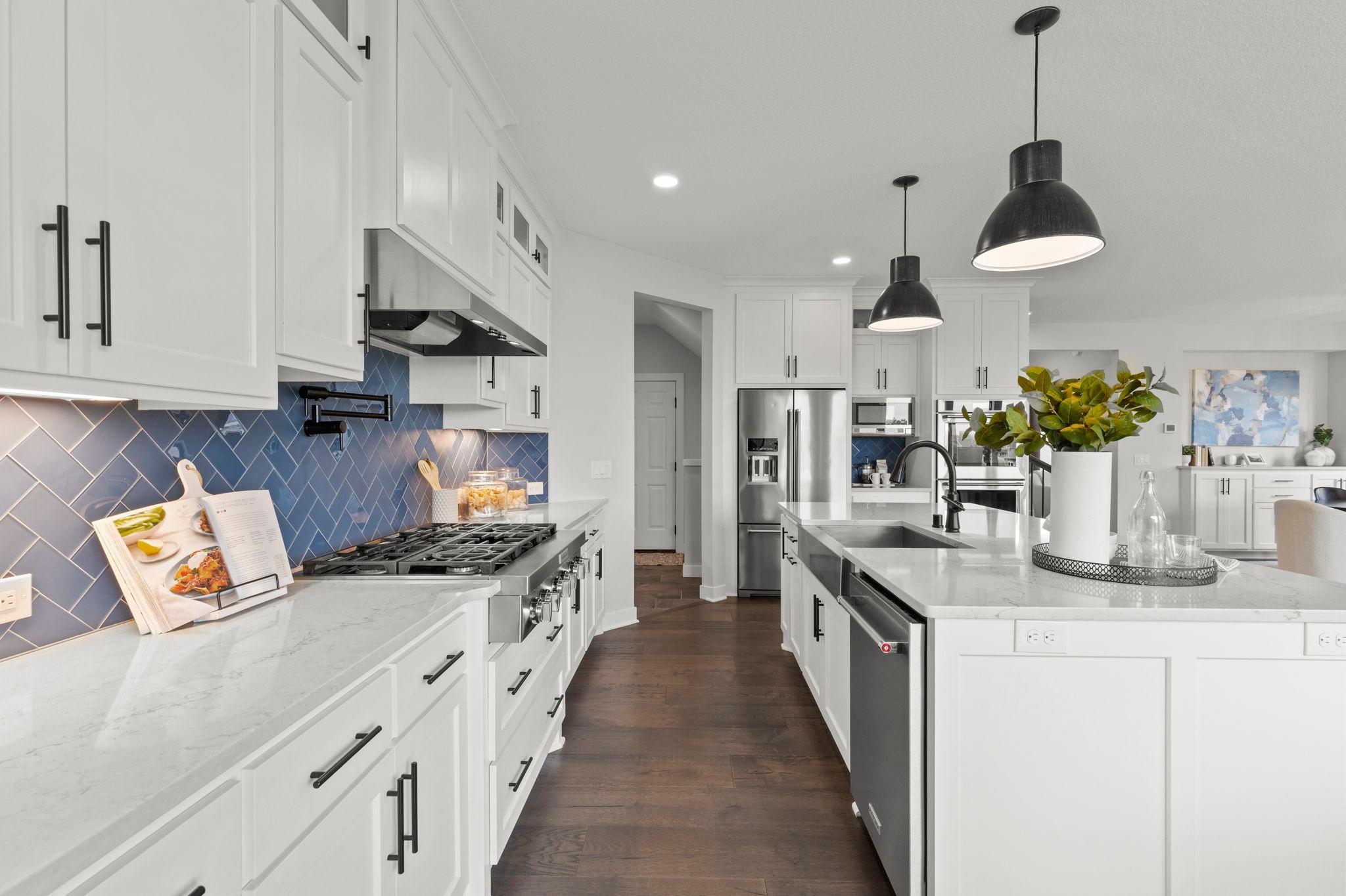 Stainless steel appliances include a double oven and gas cooktop, complemented by a convenient pot filler and sleek tile backsplash.