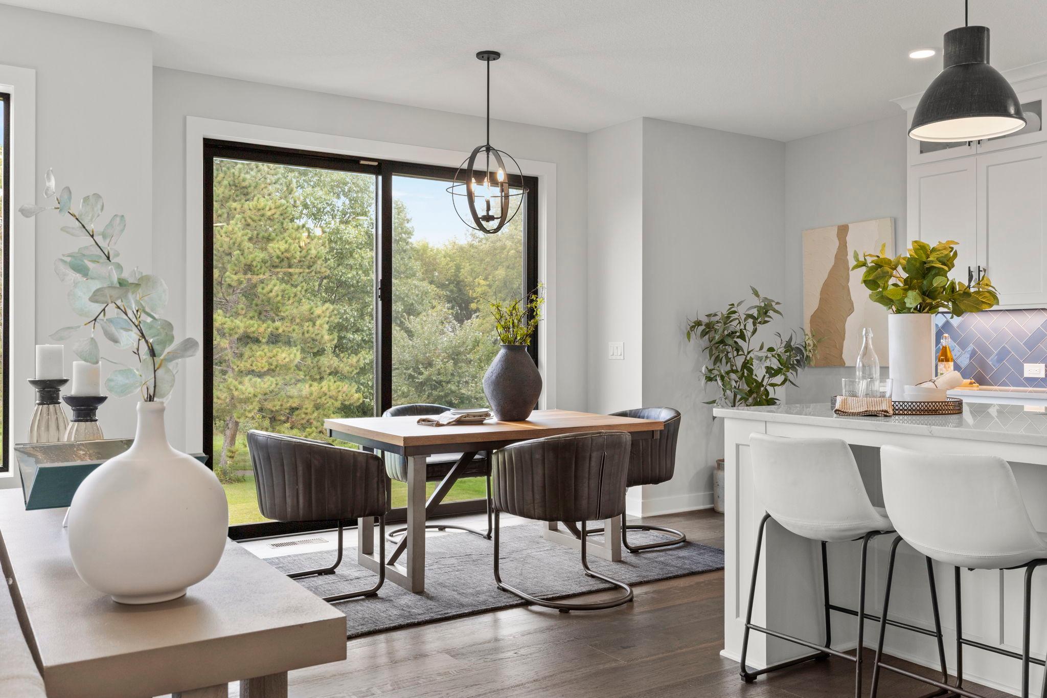 The informal dining area features a modern chandelier and Pella sliding glass door leading to a future deck.