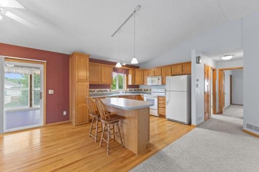 Another view of the kitchen highlights the home's open and functional design, featuring beautiful hardwood floors, soaring vaulted ceilings, and abundant natural light.