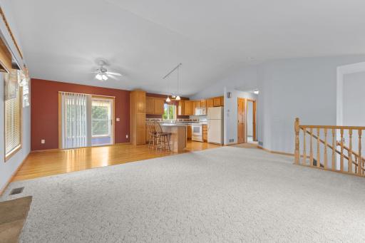 This view highlights the heart of the home, showcasing the seamless flow between the kitchen, dining area, and inviting 3-season porch. Rich hardwood floors add warmth and character.