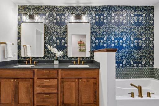 Primary bathroom with dual vanities, wallpaper, soaking tub and walk in shower