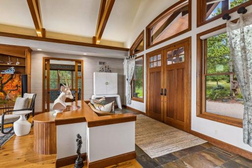 Grand double door entry into great room with soaring vaulted, beamed ceilings