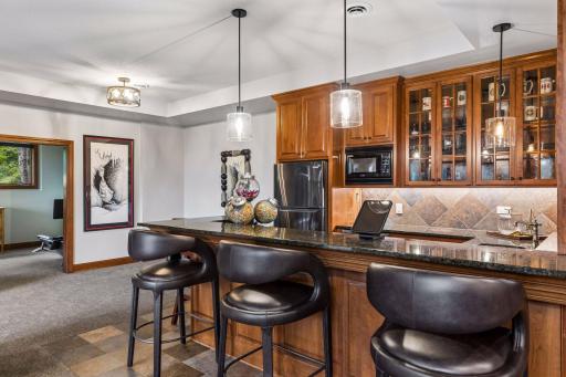 Wet bar with cherry cabinetry, granite counters and seating for three