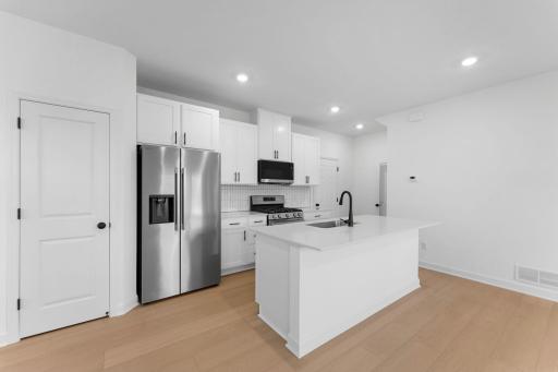 A multifunctional center island pairs with abundant cabinetry and all-new stainless steel appliances to create a sleek design in this breezy kitchenâperfect for cooking meals of all sizes.