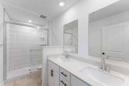 A dual-sink vanity with separate plate-glass mirrors and a glass-enclosed shower promote timely routines