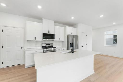 A multifunctional center island pairs with abundant cabinetry and all-new stainless steel appliances to create a sleek design in this breezy kitchenâperfect for cooking meals of all sizes.