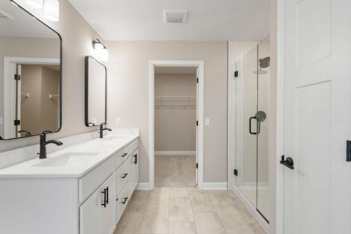 Featuring a sophisticated dual-sink vanity with separate mirrors, this en-suite bathroom ensures streamlined morning routines