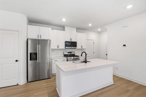 A multifunctional center island pairs with abundant cabinetry and all-new stainless steel appliances to create a sleek design in this breezy kitchenâperfect for cooking meals of all sizes.