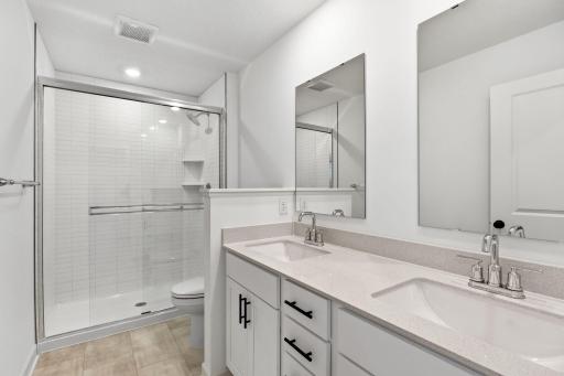A dual-sink vanity with separate plate-glass mirrors and a glass-enclosed shower promote timely routines