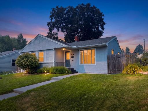 WELCOME TO 471 WHITE BEAR AVENUE. Dusk settles over St. Paul's Battle Creek neighborhood, porch light spilling gold across the lawn while a towering shade tree stands guard overhead. This is the kind of arrival you remember.