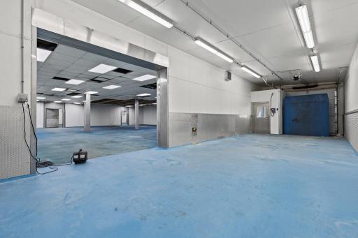 Dedicated loading and handling space featuring an overhead door, protective wall panels, and convenient access to adjoining work areas.