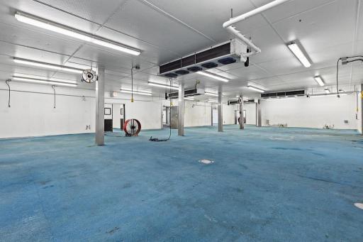 Impressive open-concept industrial production space featuring expansive floor area, overhead mechanical systems, multiple support columns, and bright commercial lighting.