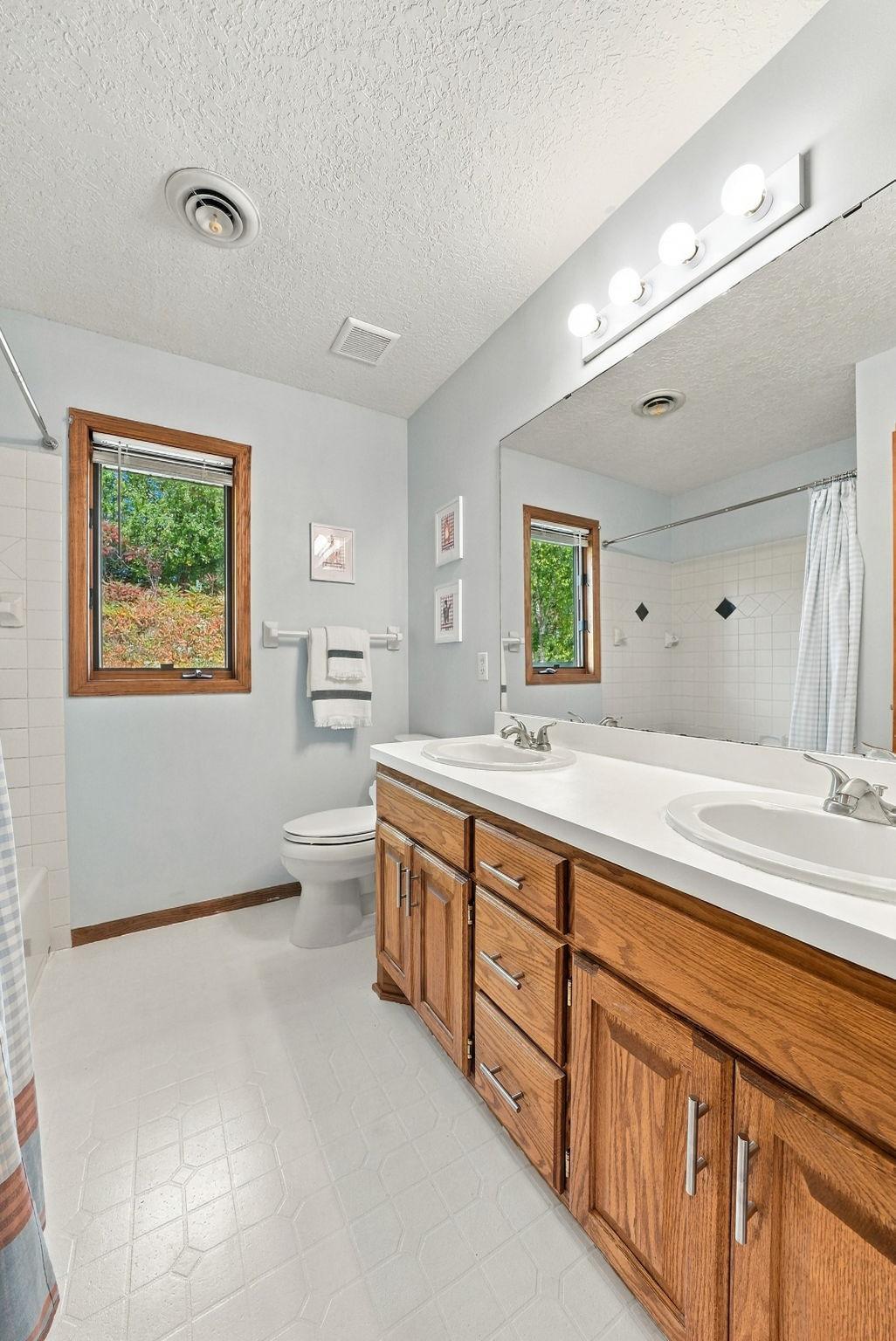 Full sized bathroom with double vanity on upper level